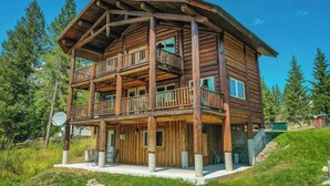 Eine mehrstöckige Holzhütte mit einem Balkon im zweiten Stock, umgeben von viel Grün.