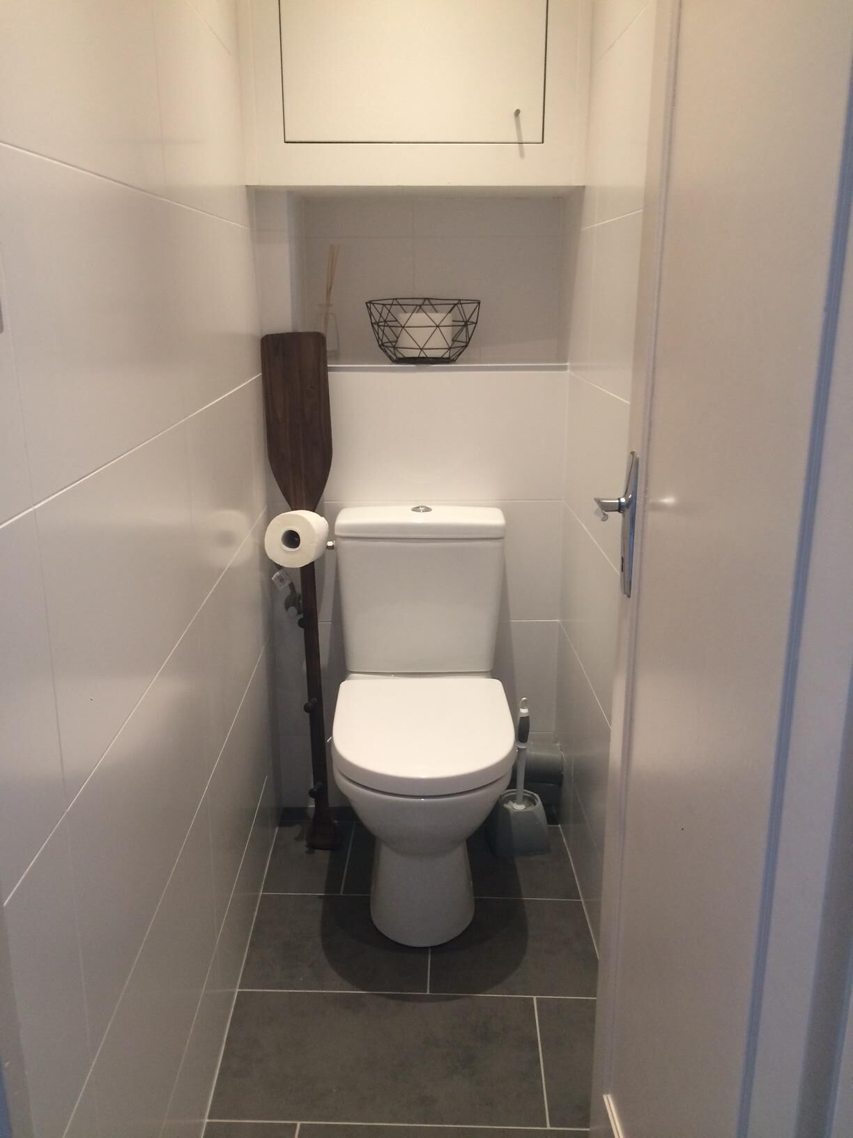 A small, modern bathroom with a toilet, a toilet paper holder, and a bidet.