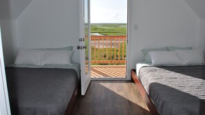 A bedroom with two beds, a wooden deck, and a view of a green landscape. - King size bed! Freeport Surfside Beach Bungalow Ocean & BayViews,Steps from Ocea (Surfside Beach)