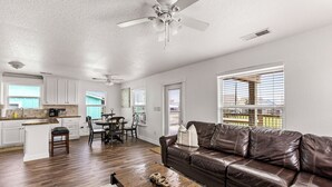 A spacious living room with a brown leather sofa, a wooden coffee table, and a dining area with a table and chairs. - King size bed! Freeport Surfside Beach Bungalow Ocean & BayViews,Steps from Ocea (Surfside Beach)