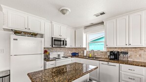A kitchen with white cabinets, a granite countertop, a stainless steel refrigerator, a microwave, and a dishwasher. - King size bed! Freeport Surfside Beach Bungalow Ocean & BayViews,Steps from Ocea (Surfside Beach)