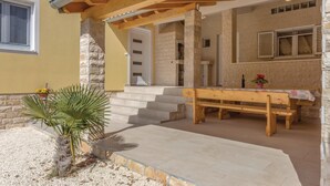 A stone building with a wooden bench and a table outside, a staircase leading to a door, and a palm plant in the foreground. - Nice home in Liznjan with WiFi (Liznjan)