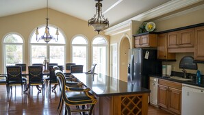 A spacious kitchen with a large island, wooden cabinets, and a chandelier.