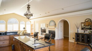 A spacious kitchen with a large island, wooden cabinetry, and a chandelier.