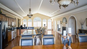 A spacious kitchen with a large island, wooden cabinets, and a chandelier.