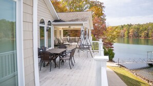 A covered deck with outdoor furniture and a view of a lake.
