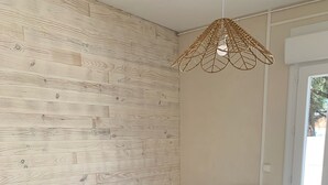 Ein Schlafzimmer mit einem hölzernen Kopfteil, einem weißen Nachttisch, einem türkisfarbenen Kopfkissen und einem aufgerollten Handtuch auf dem Bett.