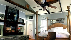 A bedroom with a four-poster bed, a fireplace, and a ceiling fan. - Romantic Spa Experience in Luxurious Creekside Honeymoon Cottage in the Landings (Steinhatchee)
