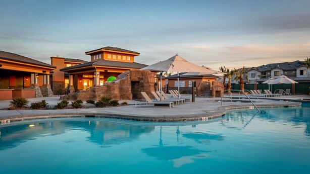 Um resort com piscina, espreguiçadeiras e uma grande formação rochosa.