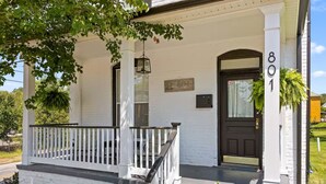 Ett vitt hus med en svart dörr, husnummer 801, och en veranda med ett vitt räcke.