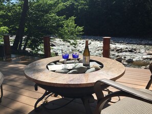 A round table with a bottle of wine and two glasses on a deck overlooking a rocky river. - Spectacular Views! (Lincoln)