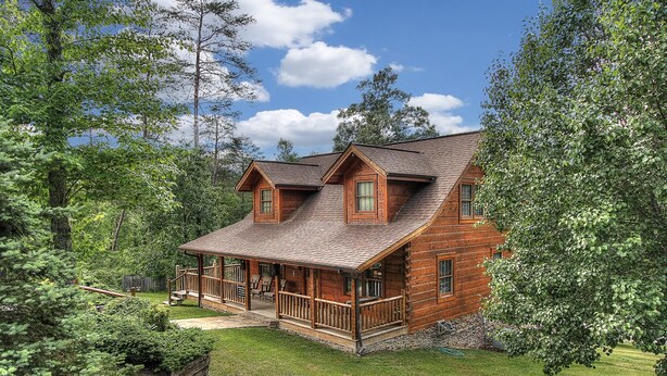 A log cabin with a porch, surrounded by trees and a grassy yard. - Bears Den, Pigeon Forge, Arcade game, Hot Tub (Pigeon Forge)