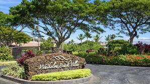 A sign for Waikoloa Beach Villas with a landscaped area featuring various plants and trees. - 2026 Waikoloa Hilton pool pass included 6 guests daily, available through 2026! (Waikoloa Village)