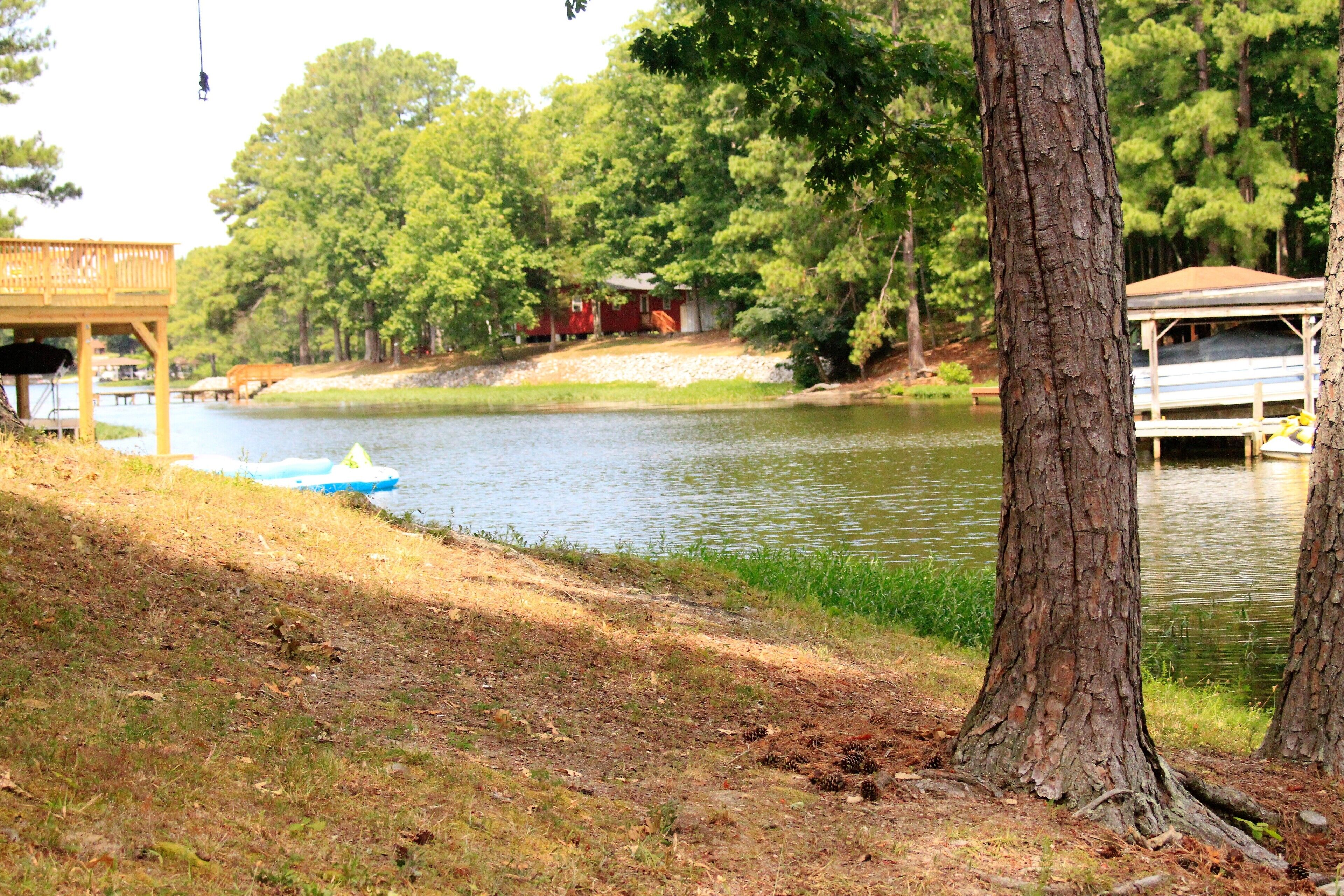 A lakeside cabin with a dock, surrounded by trees and a grassy area.