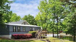 A lakeside cabin with a deck, stairs, and a small dock. - Beautiful Waterfront Home on Lake Gaston + Pontoon Rental Option (Henrico)