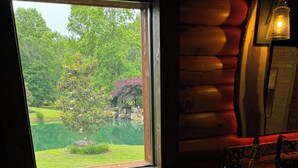 Une baignoire en pierre avec un plateau en bois, une fenêtre donnant sur un jardin et un mur en pierre.
