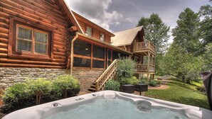 Une cabane en rondins dotée d’un bain à remous, de fondations en pierre et d’une terrasse en bois.