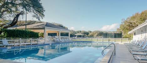 Piscina com borda azulejada, espreguiçadeiras e um pavilhão coberto.