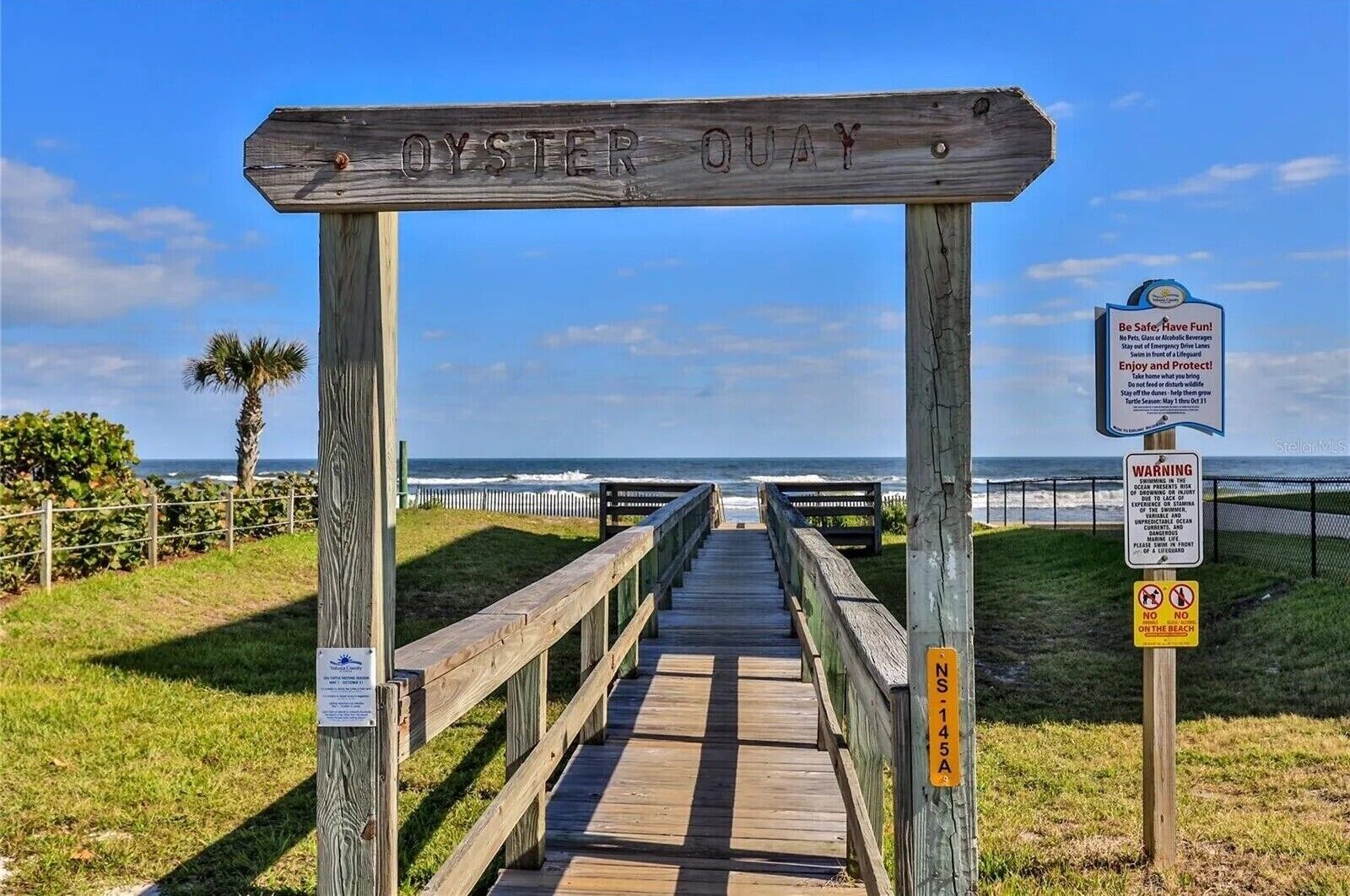 Un paseo marítimo de madera que lleva al océano, con un cartel que dice "OYSTER QUAY".