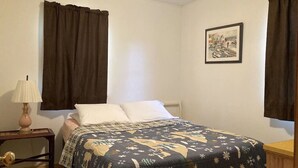 Ein Schlafzimmer mit einem Bett, einem Nachttisch mit Lampe und einem gerahmten Bild an der Wand.