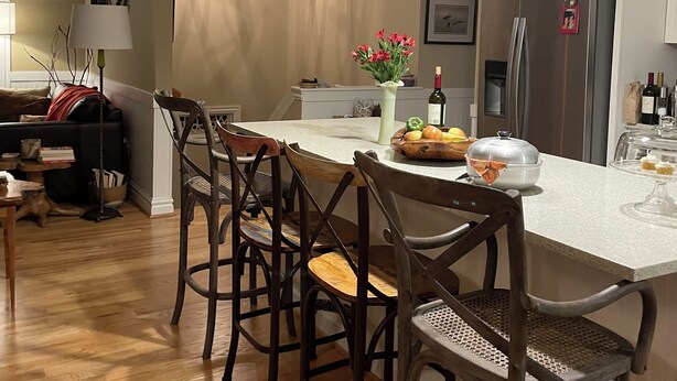 A modern kitchen with a central island, wooden chairs, pendant lighting, and a refrigerator. - Direct Beach Access, Priv. Saltwater Pool,  Hottub, Elevator, BR 5; bath 5 (Kill Devil Hills)