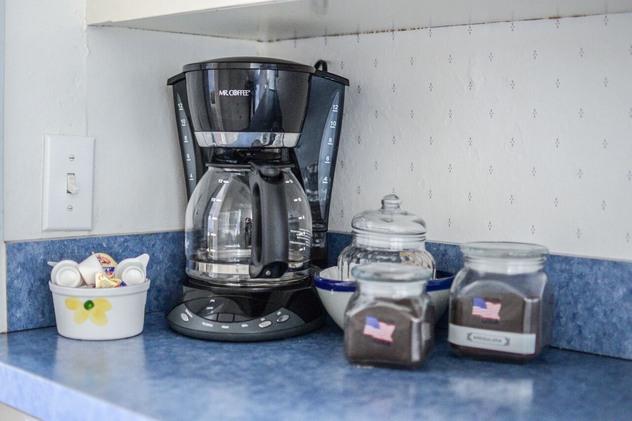A coffee maker, measuring cups, and spice jars on a kitchen counter.
