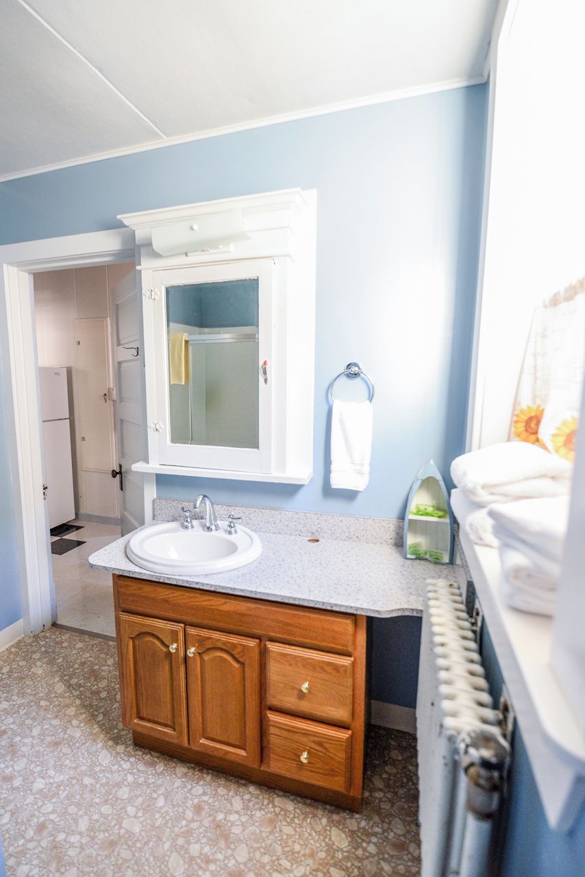 A bathroom with a white sink, wooden vanity, and a glass shower enclosure.