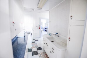 Une salle de bain d’hôtel moderne, dotée d’un grand lavabo, d’un miroir et d’un sol à motifs.