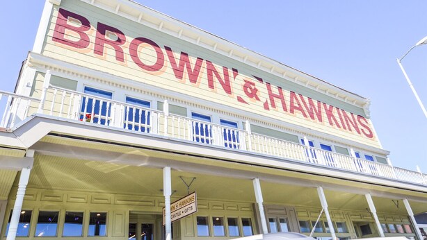 Un edificio con un gran letrero que dice "BROWN & HAWKINS" y un balcón con barandillas.