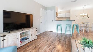 Una sala de estar moderna con un televisor de pantalla plana, suelo de madera y un sofá azul claro.