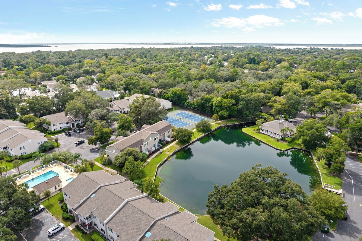 A residential area with houses, a swimming pool, and a lake.
