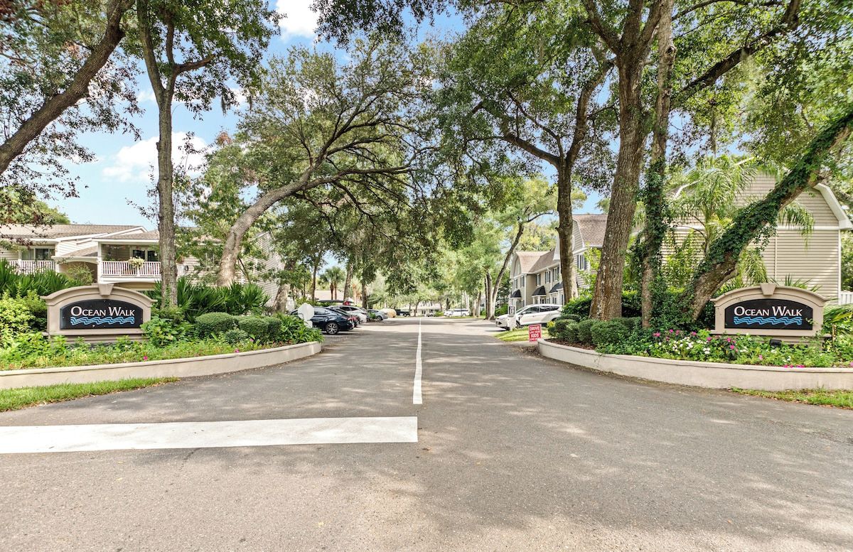 Una calle residencial con casas, árboles y un letrero que dice 'Ocean Walk'.