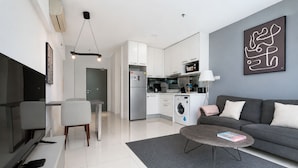 Una sala de estar moderna con un sofá, una mesa de centro, un televisor y una cocina al fondo.