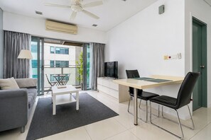Una sala de estar moderna con un sofá, una mesa de comedor con sillas, un televisor y un balcón con cortinas.