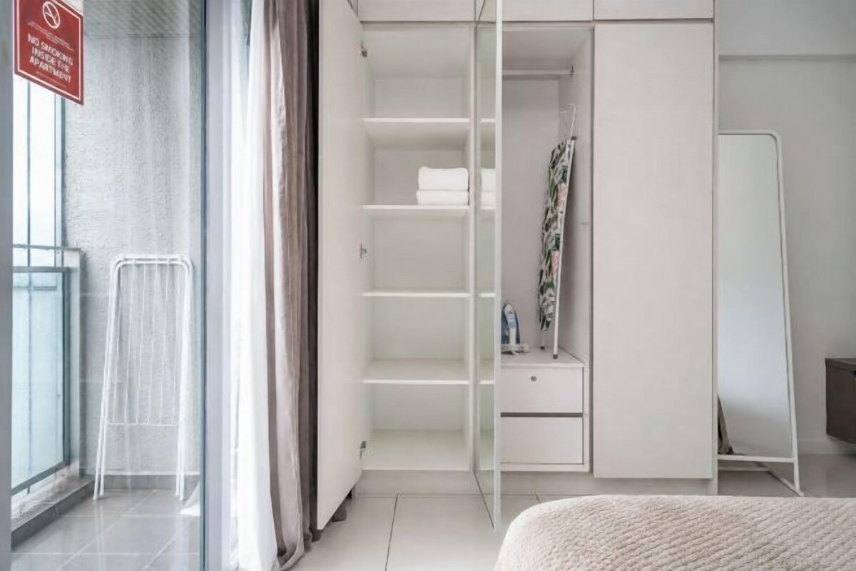A hotel room with a sliding closet, a bed, a window with curtains, and a view of the outside.