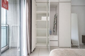 A hotel room with a wardrobe, a mirror, a radiator, and a window with curtains. - Summer Suites KLCC Apartments By Soulasia (Kuala Lumpur)