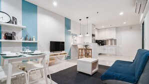 Una sala de estar moderna con comedor, cocina y televisor.