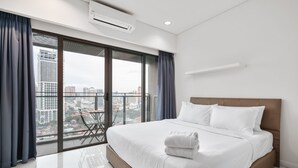 Una habitación de hotel moderna con una cama grande, un balcón con vistas a la ciudad y una pequeña mesa con sillas.