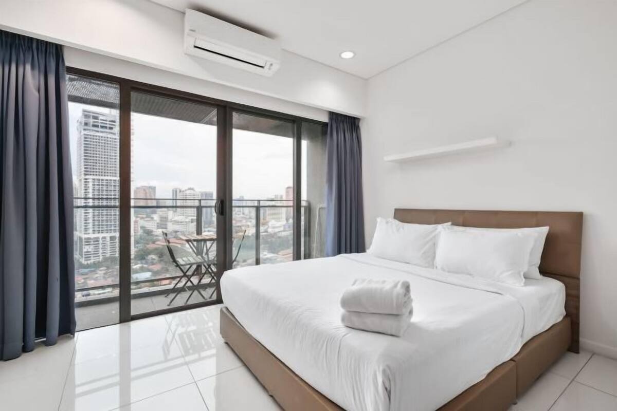 Ein modernes Hotelzimmer mit einem großen Bett, einem Balkon mit Stadtblick und einem Esstisch.