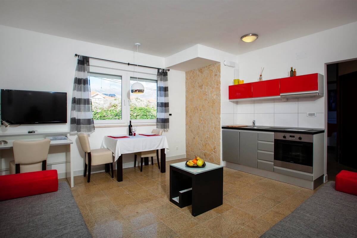 A compact living space with a dining area, kitchen, and a TV.