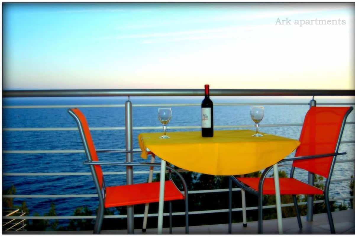 A table with a bottle of wine and two glasses, set against a view of the sea.