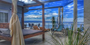 A balcony with a bed, lounge chairs, and a view of the sea. - Ark Beach Hotel (Split)