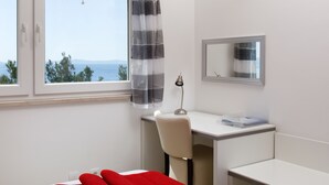 A hotel room with a desk, chair, and a bed with red pillows. - Ark Beach Hotel (Split)