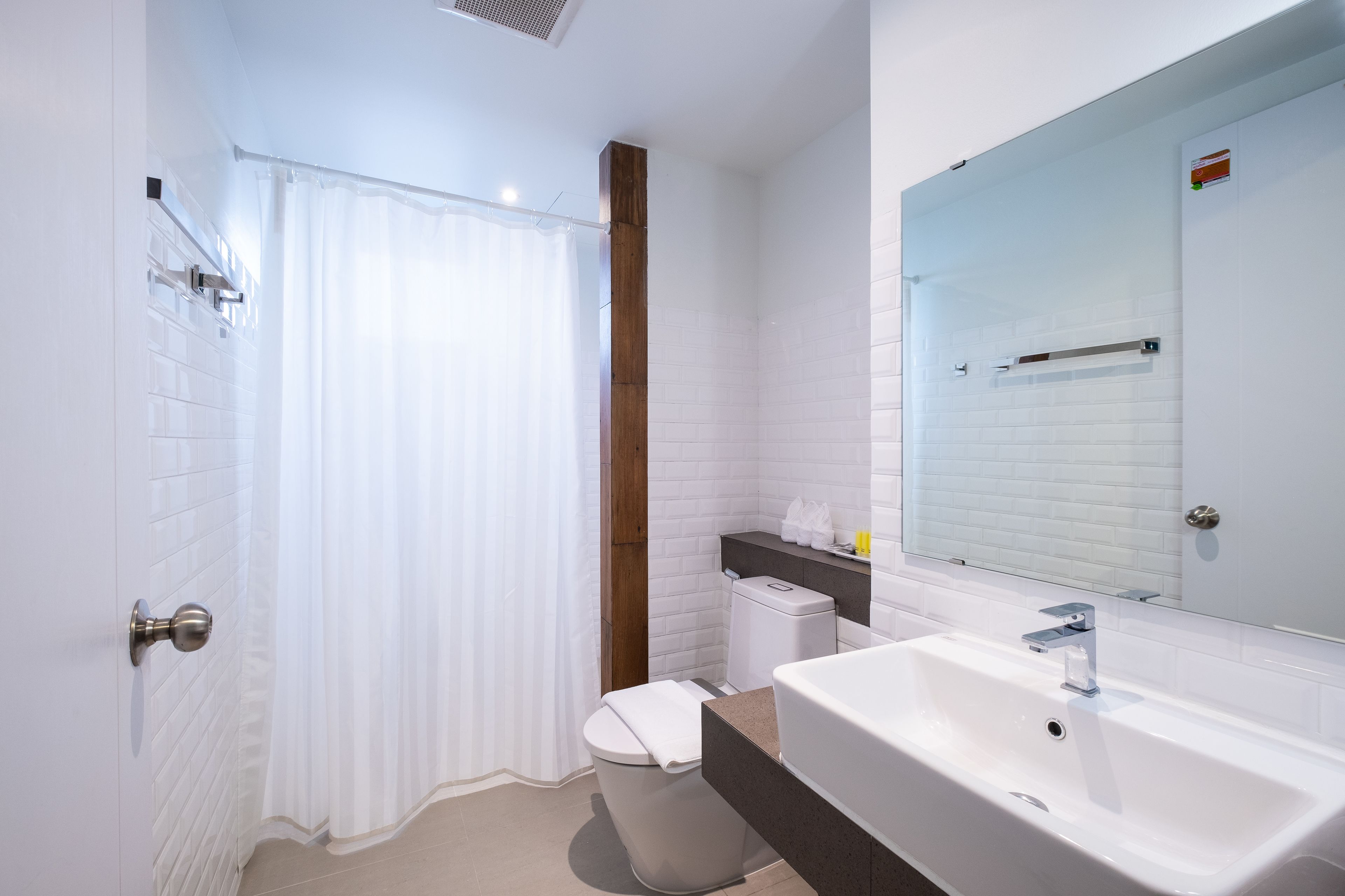 A modern bathroom with a white sink, a mirror, and a shower curtain.