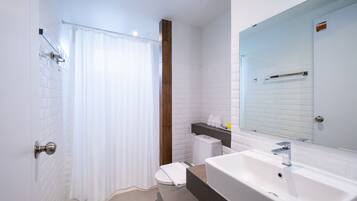 A modern bathroom with a white sink, a mirror, and a shower curtain.