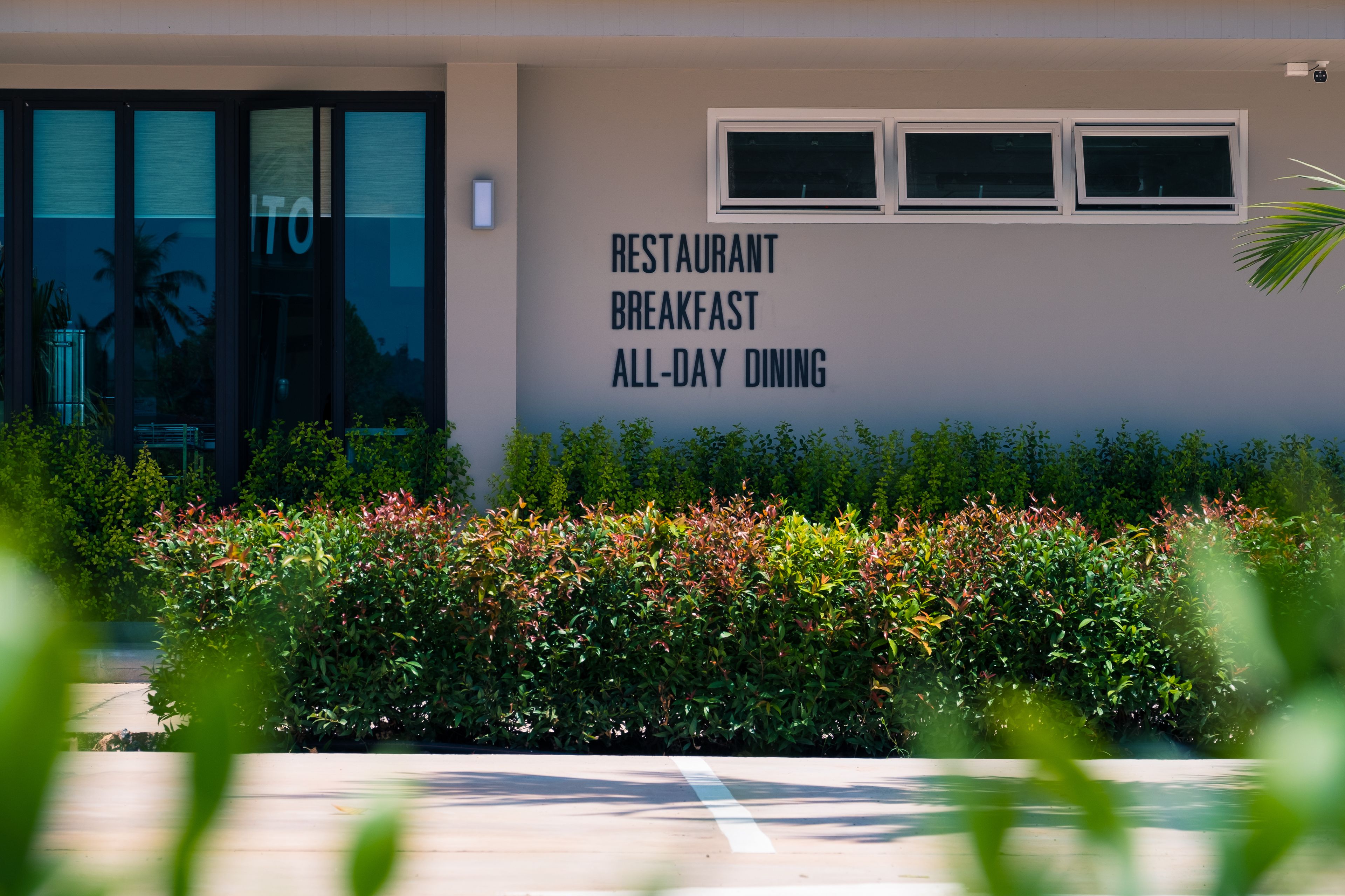A building with a sign stating "RESTAURANT BREAKFAST ALL-DAY DINING" and a glass door entrance.
