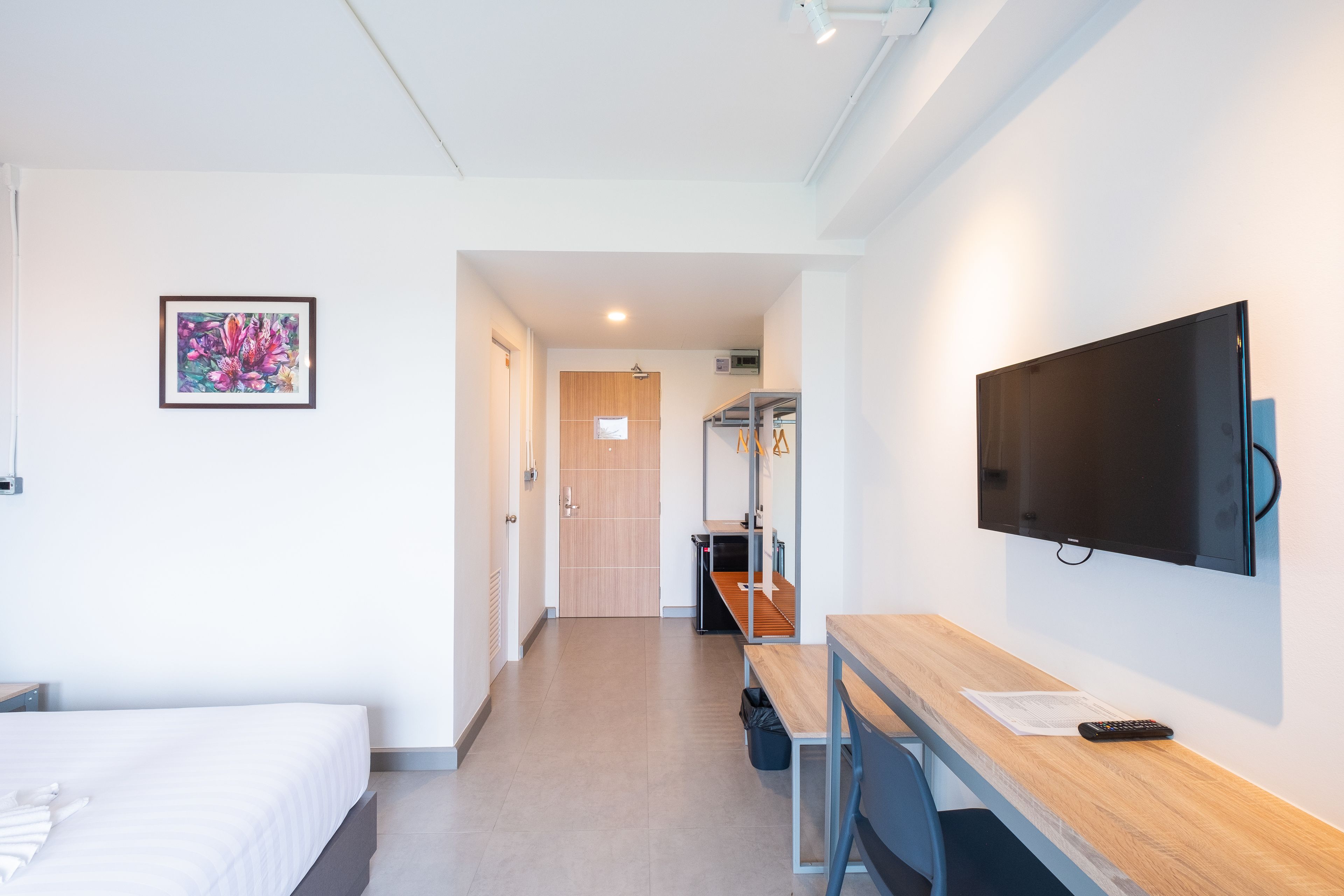 Habitación de hotel con cama, escritorio, silla, televisión y un cuadro en la pared.
