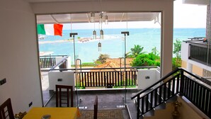 A balcony with a view of the sea, a table with a mat, and a hanging light fixture. - Queens Beach Hotel (Tangalle)