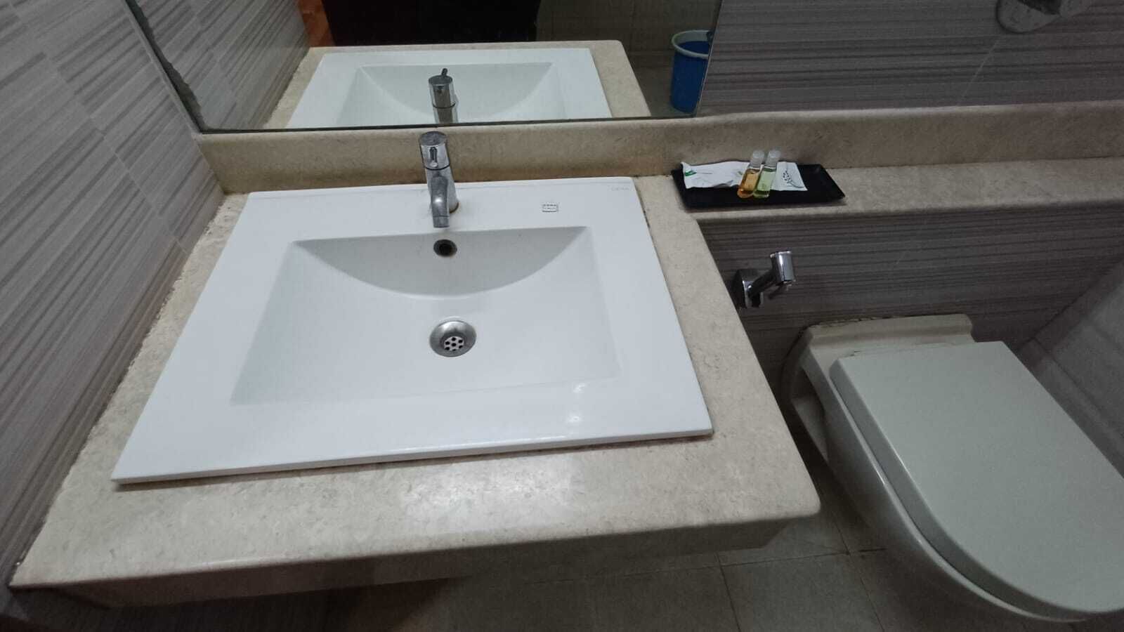 Un baño con un lavamanos blanco, un inodoro y un espejo sobre el lavamanos.