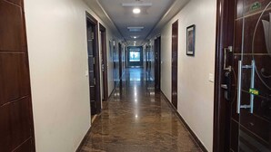 A hotel corridor with a marble floor, wooden doors, and a push button door. - Hotel Sriram JB Residency (Virudhunagar)